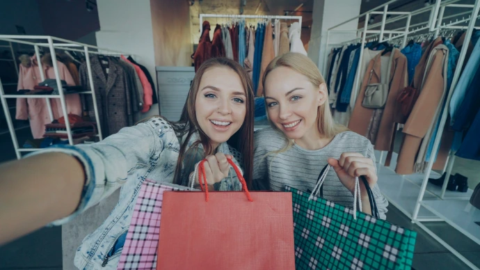 Two smiling women are shopping with bags.